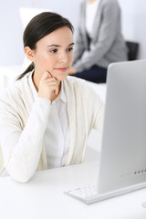 Business woman working with computer in office, female colleague at background. Headshot of Lawyer or accountant at work while sitting at the desk