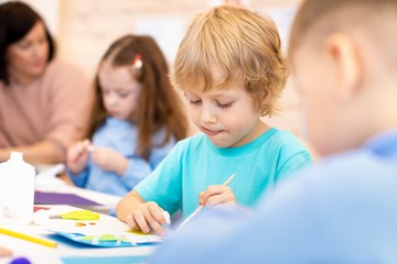 kindergarten children doing arts and crafts with teacher in daycare centre