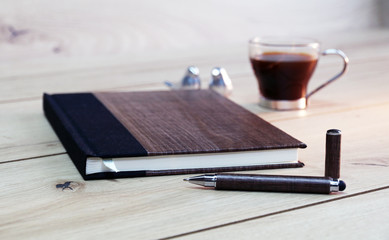 notebook on wooden  table with pen and coffee