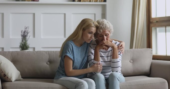 Worried young daughter consoling sad crying old senior mother