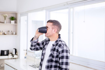 Young man drinking a cup of coffee in the kitchen