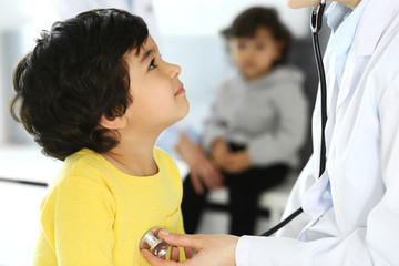 Doctor examining a child patient by stethoscope. Cute arab boy at physician appointment. Medicine and healthcare concept
