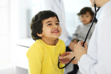 Doctor examining a child patient by stethoscope. Cute arab boy at physician appointment. Medicine and healthcare concept - Powered by Adobe
