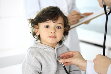 Doctor examining a child patient by stethoscope. Cute arab boy at physician appointment. Medicine and healthcare concept