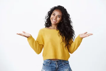 Fotobehang Kapsalon Cheerful carefree alluring african-american woman with curly dark hairstyle in yellow sweater, spread hands sideways shrugging unbothered and smiling careless, cheering have no bother  © Cookie Studio