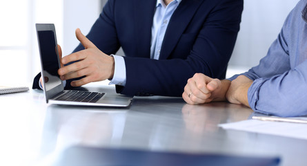 Business people using laptop computer while working together at the desk in modern office. Unknown businessman or male entrepreneur with colleague at workplace. Teamwork and partnership concept