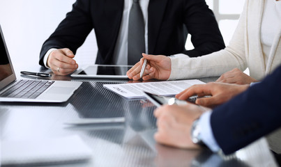 Business people discussing contract working together at meeting at the glass desk in modern office. Unknown businessman and woman with colleagues or lawyers at negotiation. Teamwork and partnership