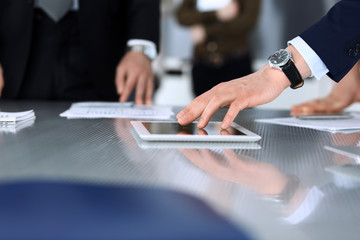 Business people using tablet computer while working together at the desk in modern office. Unknown businessman or male entrepreneur with colleague at workplace. Teamwork and partnership concept