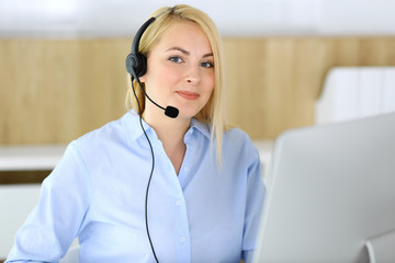 Call center. Blonde business woman sitting in headset at customer service office. Concept of telesales business or home office occupation