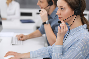 Call center. Group of casual dressed operators at work. Focus on business woman in headset at...