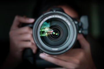 photographer  take pictures Snapshot with camera. man hand holding with camera looking through lens.Concept for photographing articles Professionally. - Powered by Adobe