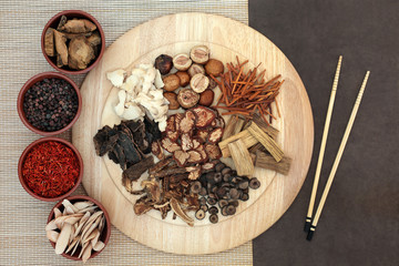 Traditional Chinese herbs used in herbal medicine in bowls, on a wooden board, bamboo and lotka paper background with chopsticks.  - obrazy, fototapety, plakaty
