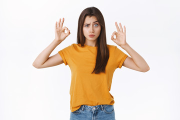 Playful, silly and cute girl in yellow t-shirt grimacing, making funny faces as showing okay, ok...