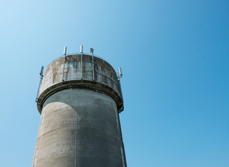 Large concrete water tower showing mobile phone communications antennas attached.