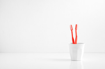 Group of red toothbrush in a plastic cup with a blank space for a text, toothbruch in bathroom