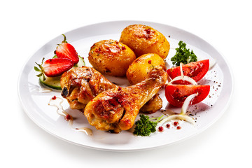 Grilled chicken drumsticks with baked potatoes and vegetables