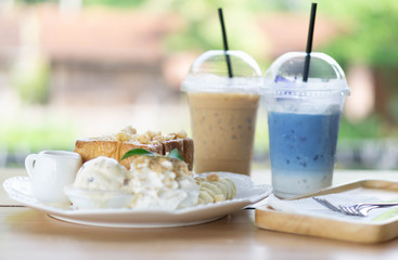 Honey toast dessert with ice coffee and milk drink on wood table, selective focus