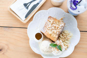 Honey toast dessert with ice coffee and milk drink on wood table, top view