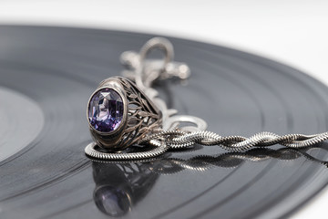 A silver chain with an elegant design and a ring on a vinyl record