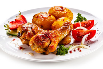Grilled chicken drumsticks with baked potatoes and vegetables