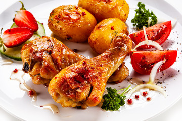 Grilled chicken drumsticks with baked potatoes and vegetables