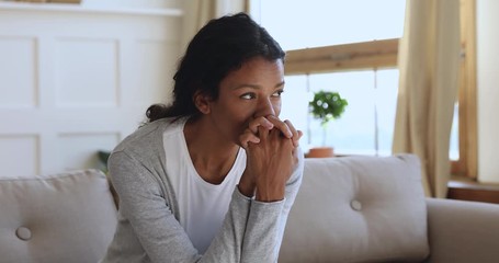 Anxious thoughtful african woman on sofa looking away feel depressed