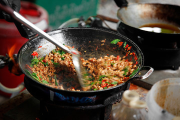 cooking Thai stir-fried minced pork with basil in the metal pan with stir fry spatula