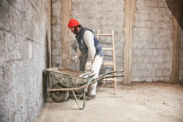 Real construction worker making a wall inside the new house.