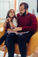 Fototapeta premium Father and his cute daughter reading Christmas fairy tales