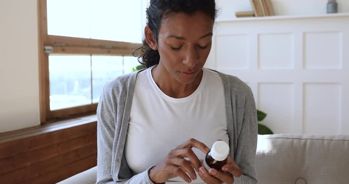 Young african woman read drug medicine prescription label, close up