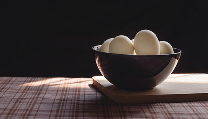 Many duck eggs on the old table and black background with morning sun light in the kitchen,Eggs are high-protein foods, children of growing age should eat eggs daily, Selective focus.