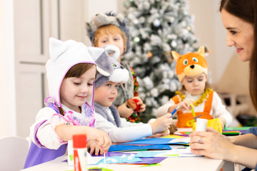 Kids with teacher make hands crafts in kindergarten. Children prepare to christmas in daycare....