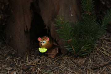 wooden mouse with cheese looks out of a forest hole