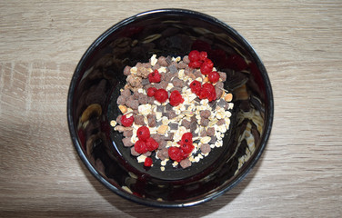 oatmeal with fresh berries in a bowl with chocolate on a table