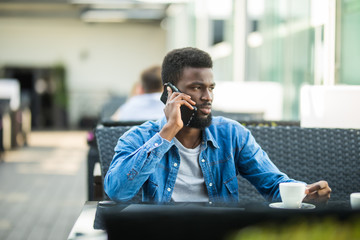 Young black man outside at cafe looking at his smartphone