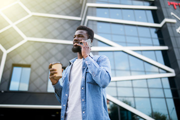 Handsome african man talking on phone at park. Young black man talking on cellphone outdoor. African american smiling guy in a happy conversation at mobile phone.