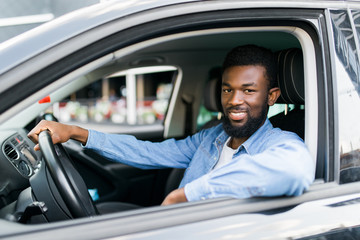 Young affluent successful african man driving his new expensive car
