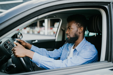Closeup portrait happy smiling young african man sitting in his new car excited ready for trip
