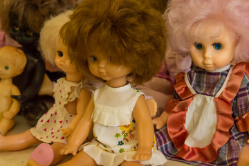 Happy childhood concept: retro toys, dolls with multi-colored hair are sitting on the table