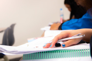 Fototapeta premium University students do quiz, test or studies from the teacher in a large lecture room. Students in uniform attending exam classroom educational school.