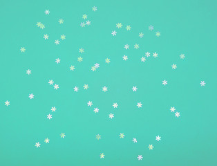 Holographic foil snowflakes confetti sparse on trendy mint colored background. Simple holiday concept. Design template. copy space for text. Top view, flat lay