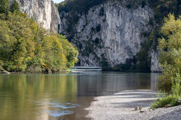 Passenger ship passing Danube breakthrough near Kelheim, Bavaria, Germany in autumn with gravel...