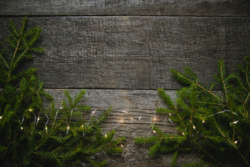 Christmas New year greeting card poster fir branches Golden sparkling garland lights on rustic tree background, magical atmosphere. The view from the top. © nadezhda