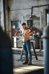 Muscled half naked man at work in an old factory.