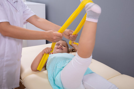 Physical Therapist Gently Helping Girl Stretching Her Leg