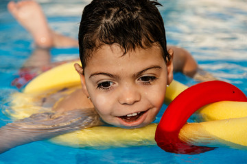 niño jugando y riendo en terapia en piscina con tubo flotador