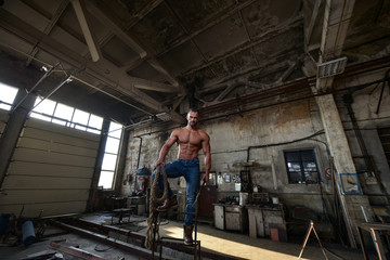 Fototapeta na wymiar Muscled half naked man at work in an old factory.