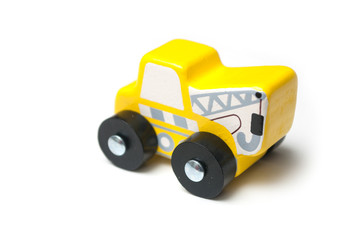 Closeup of miniature toy, wooden yellow tow truck on white background