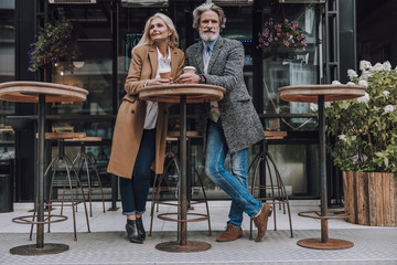 Happy adult couple enjoying coffee on the street