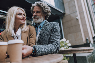 Smiling adult man is hugging woman outdoors